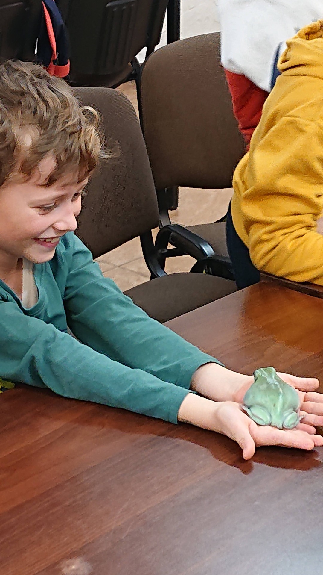 chłopiec trzyma w ręku zieloną żabkę z plasteliny.
