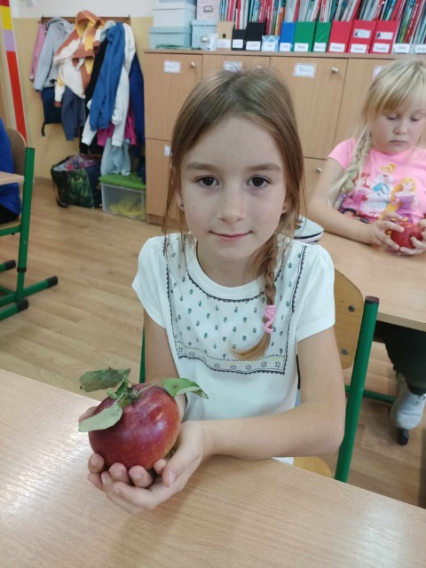Uczennica klasy I z jabłkiem.