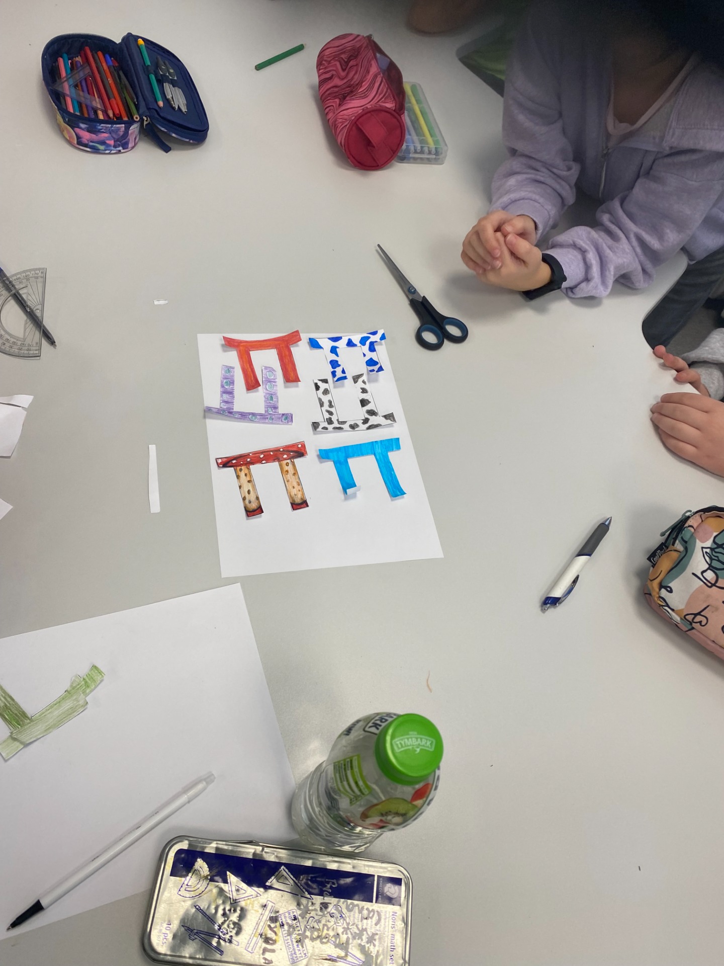 Uczniowie wykonują pracę plastyczną - parkietaż z kolorowych liter pi