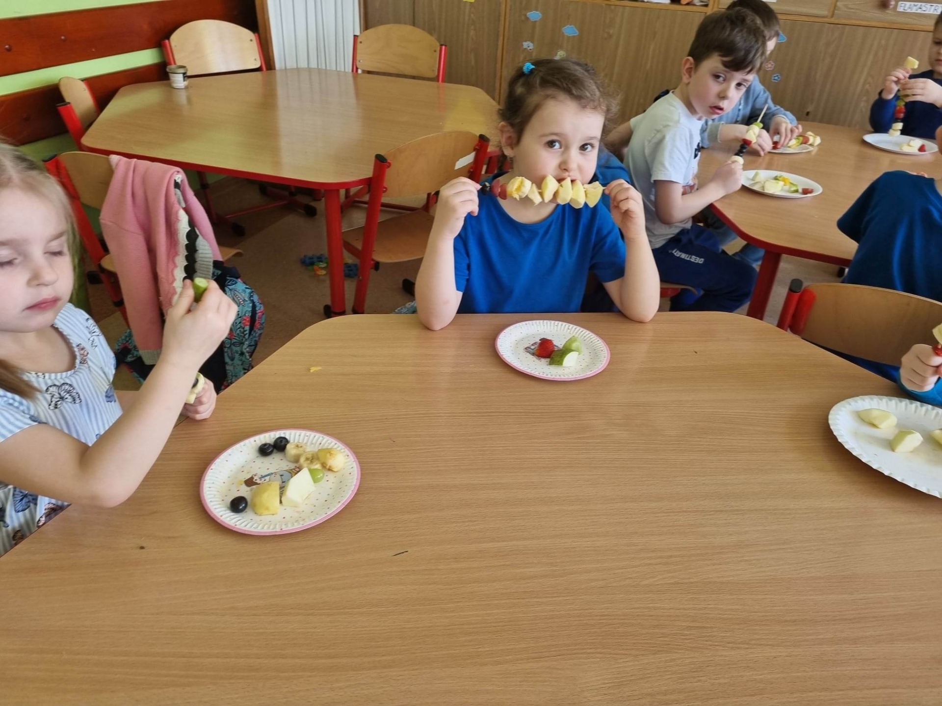 Przedszkolaki przygotowują zdrowe szaszłyki przy stoliku przedszkolnym