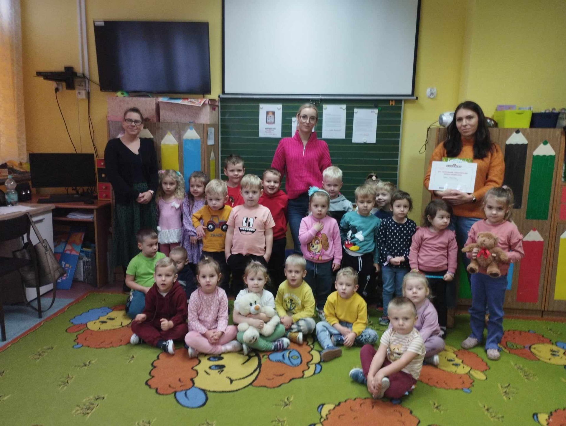 Przedszkolaki z opiekunami i panią Olgę w sali przedszkolnej.