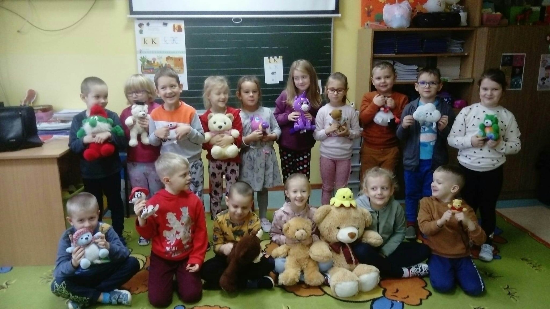 Grupa przedszkolaków z pluszowymi misiami w ręku  w sali przedszkolnej