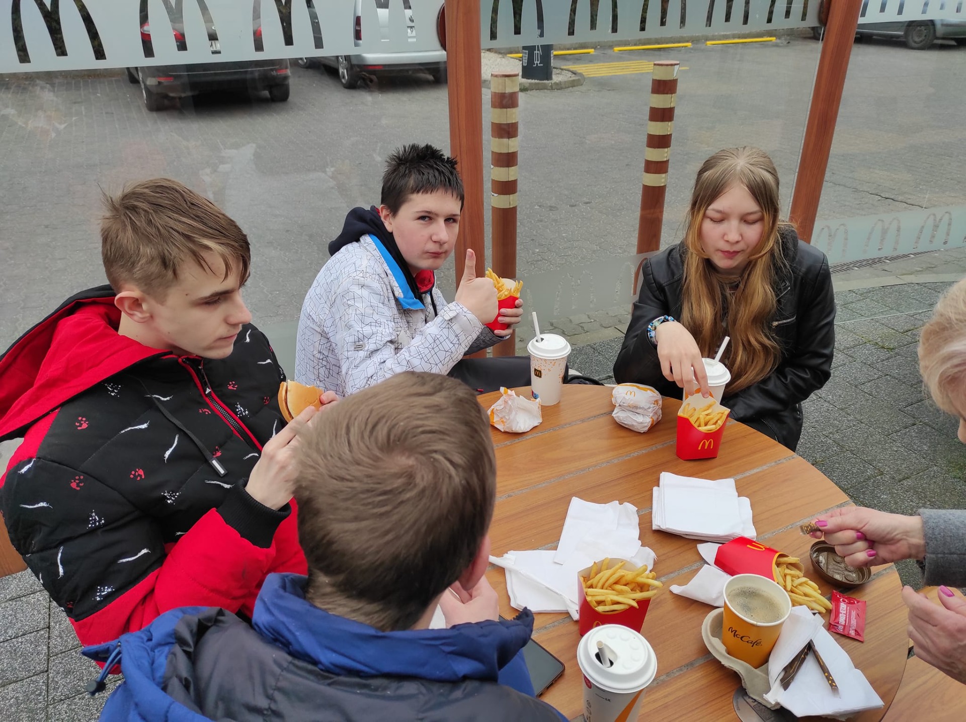 Uczniowie jedzą posiłek przy stoliku w restauracji Macdonalds