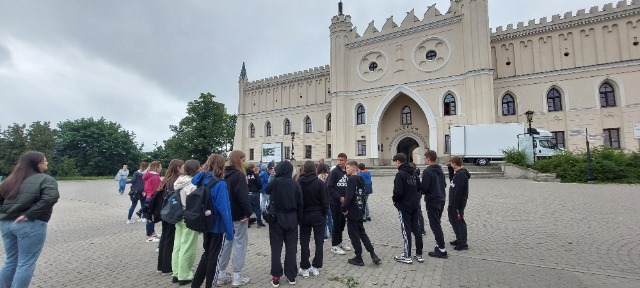 Grupa uczniów stoi budynkach należących do Starego Miasta w Lublinie
