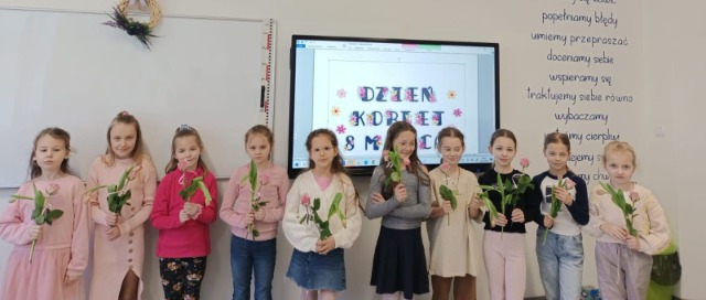 Uczniowie i uczennice z kwiatami.