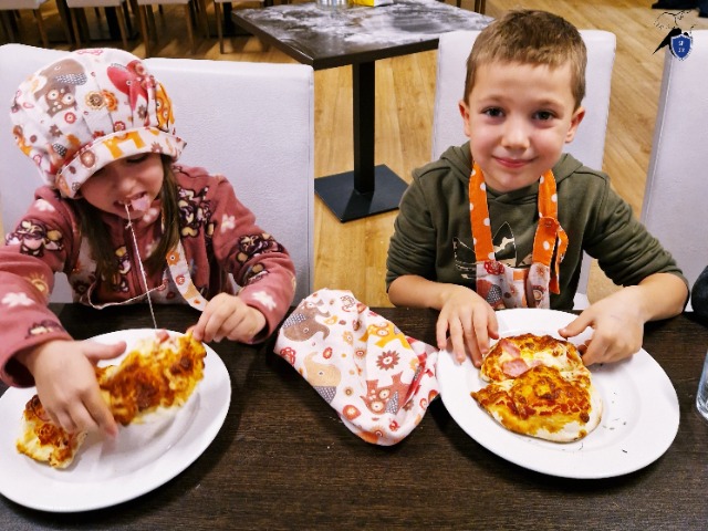 Dwoje dzieci je pizzę