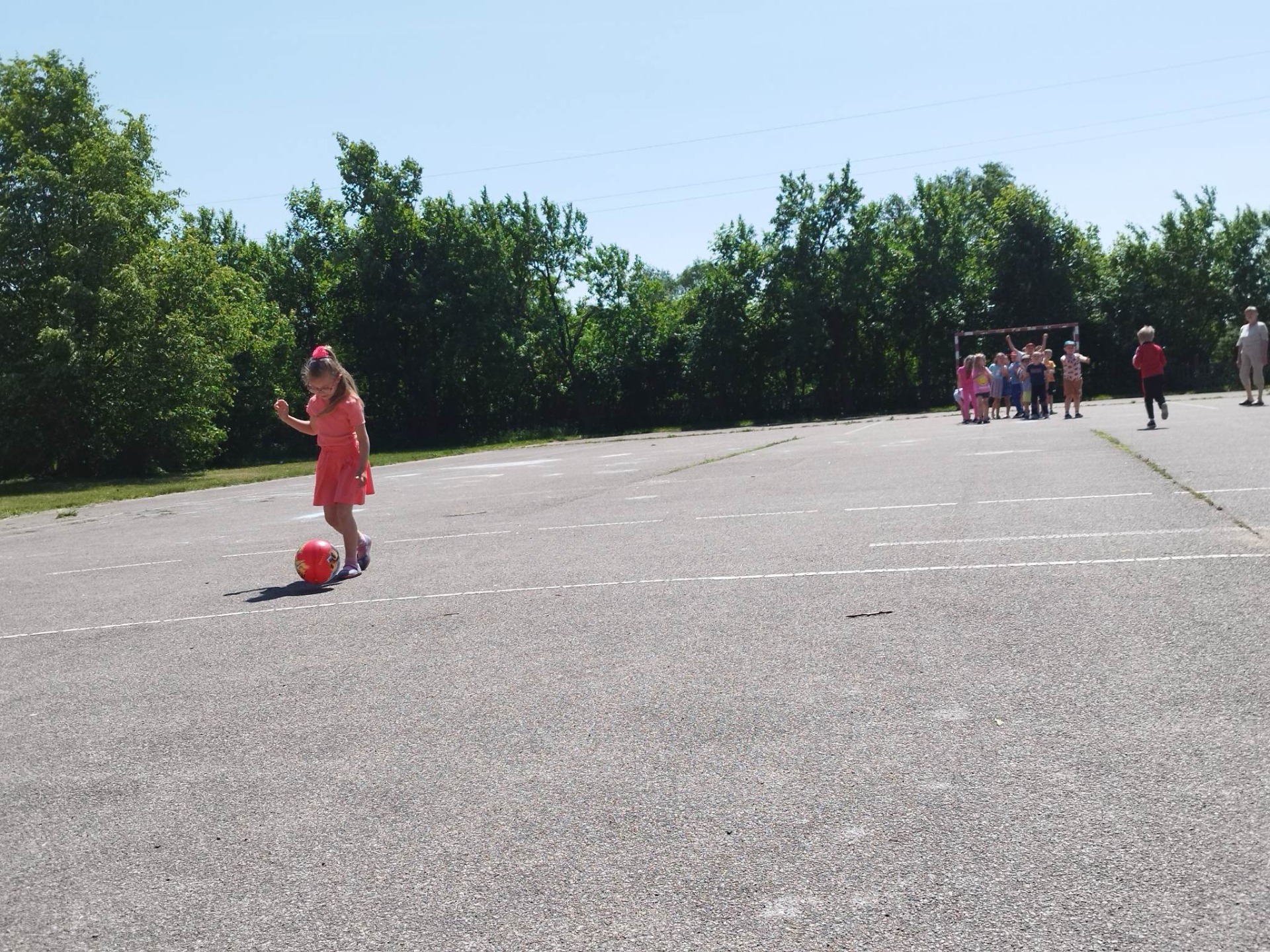 Przedszkolaki biorą udział w zabawach sportowych na szkolnym boisku