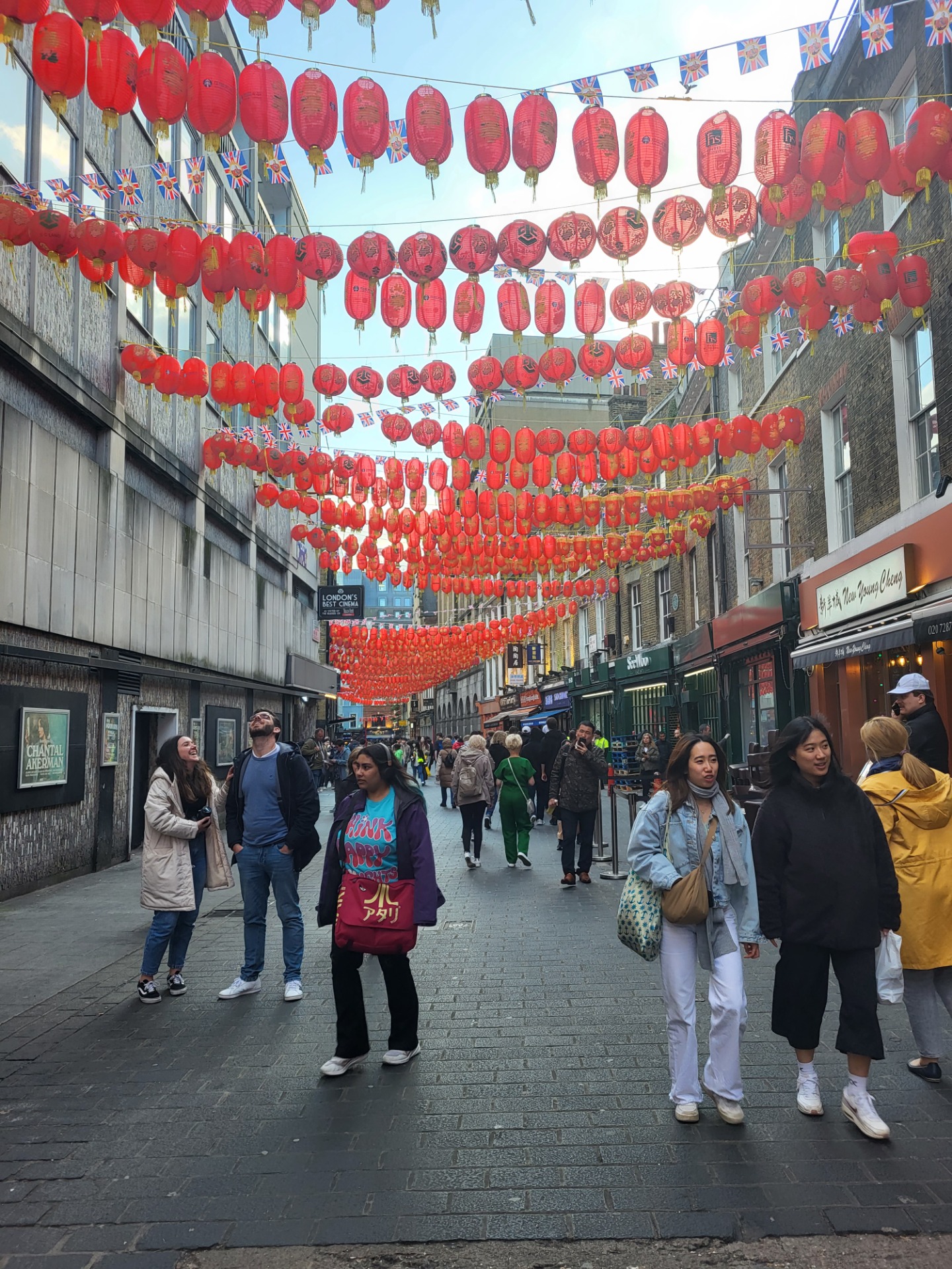 Uczniowie w jednej w uliczek. Nad głowami dekoracje z czerwonych chińskich balonów. 