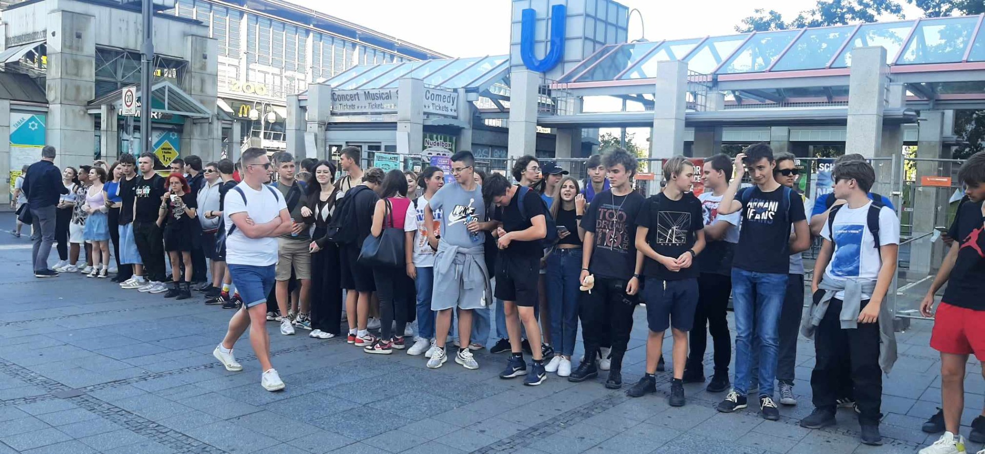 Uczniowie stoją w dwuszeregu w tle stacja berlińskiego metra. 