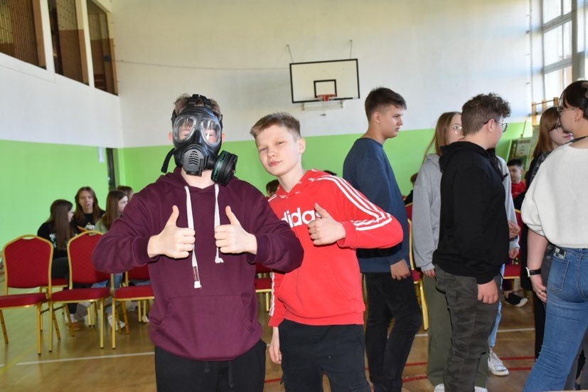 Uczniowie przymierzają maskę przeciwgazową